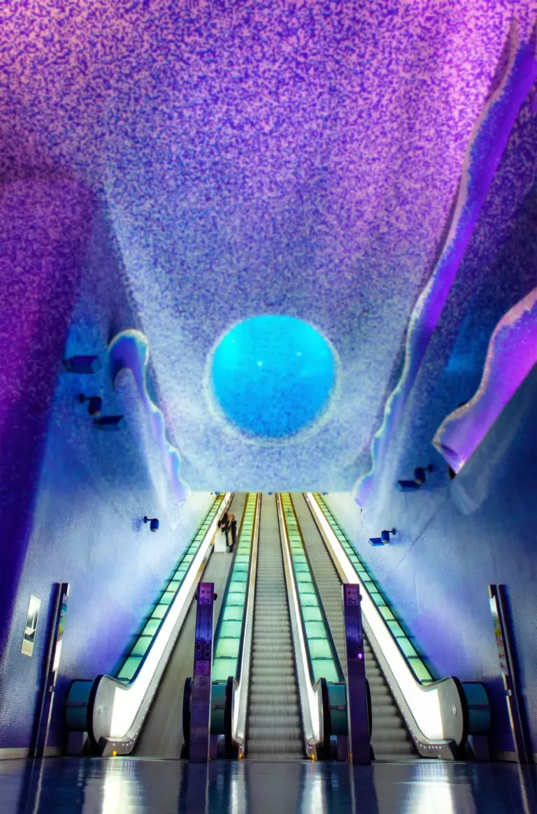 Escalators leading up through the blue and violet mosaic tunnel of Toledo Metro Station in Naples
